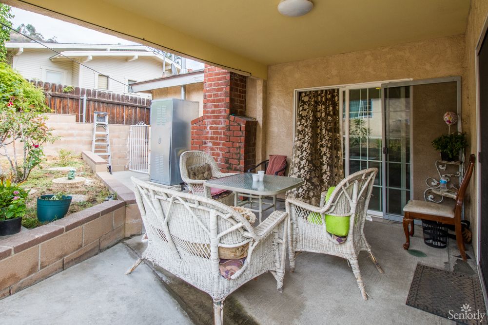 A cozy outdoor patio area with wicker chairs and a glass table, perfect for relaxing in the backyard.