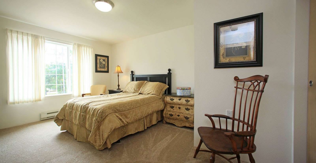 A cozy bedroom featuring a neatly made bed, a wooden nightstand, and decorative accents.