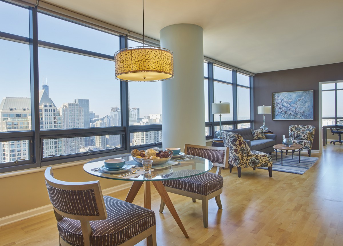 A modern apartment with a dining area and living room featuring large windows and a city view.