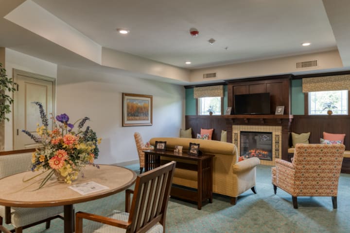 A cozy living room featuring a fireplace, television, sofa, and dining area.