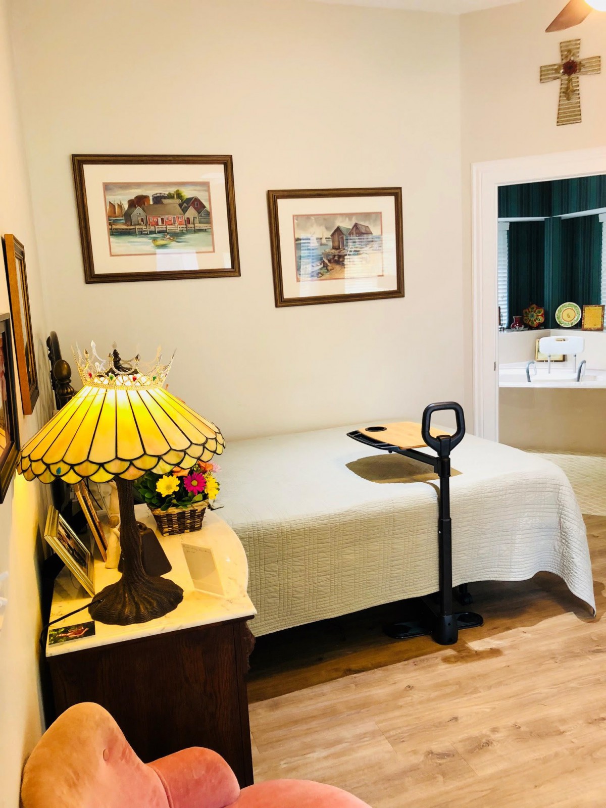 A cozy bedroom with a single bed, decorated with artwork and a classic lamp on a wooden bedside table.