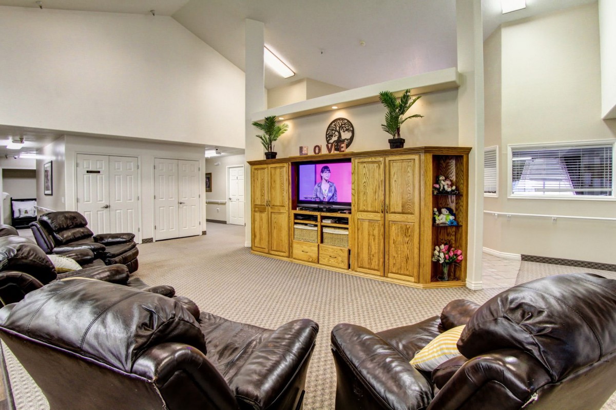 A spacious living room with cozy leather sofas and a large television in an entertainment center.