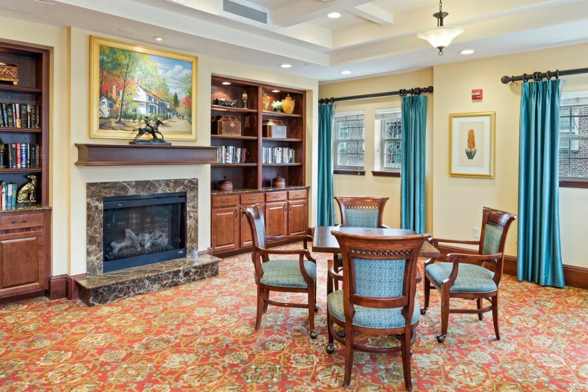 A cozy living room with a fireplace, bookshelves, and elegant furniture arrangement.