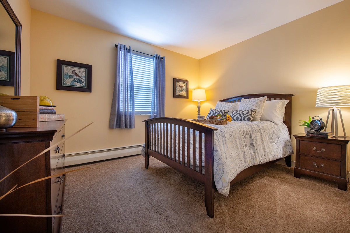 A cozy bedroom with a wooden bed frame, soft lighting, and decorative elements.