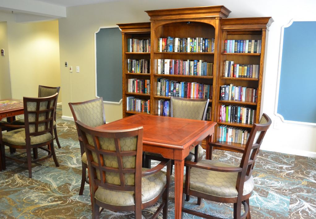 A cozy reading area with a wooden table and chairs surrounded by bookshelves filled with books.