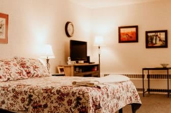 A cozy bedroom with warm lighting and a floral quilt on the bed.