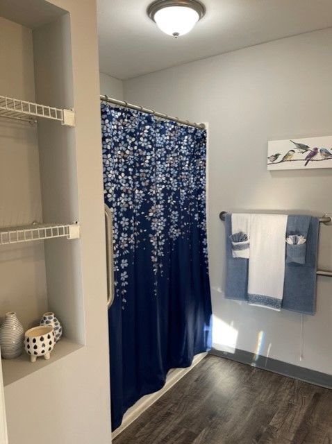 A tidy bathroom featuring a blue and white shower curtain, neatly arranged towels, and minimalist wall art.