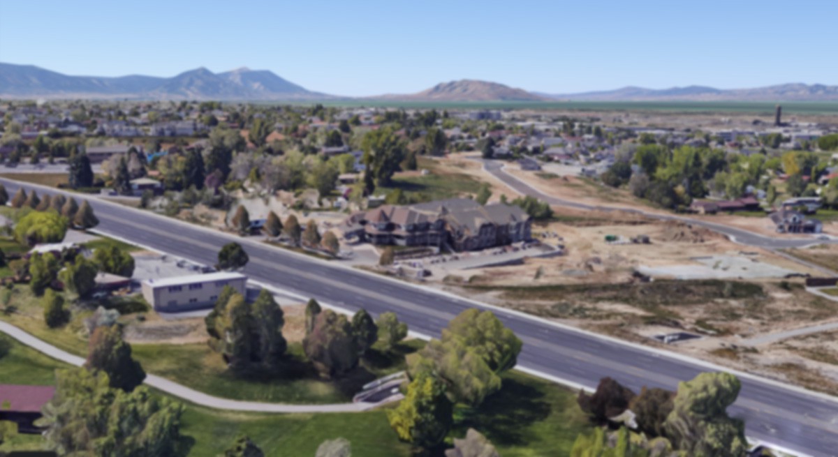 A suburban neighborhood with houses and roads, surrounded by trees with mountains in the background.
