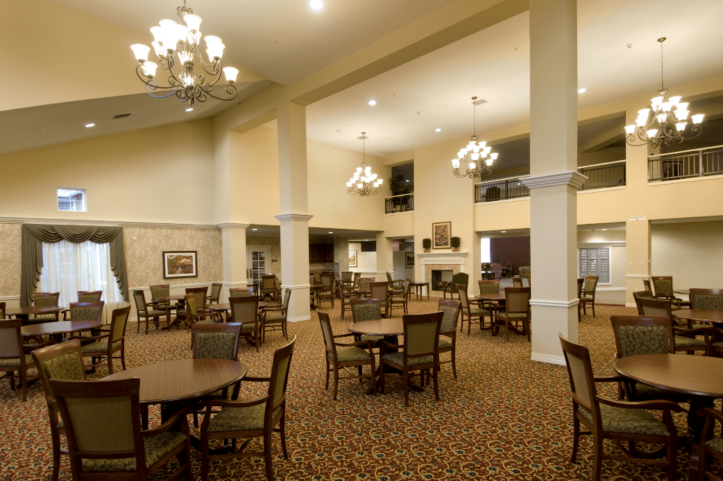 Spacious dining area with elegant chandeliers and neatly arranged tables and chairs.