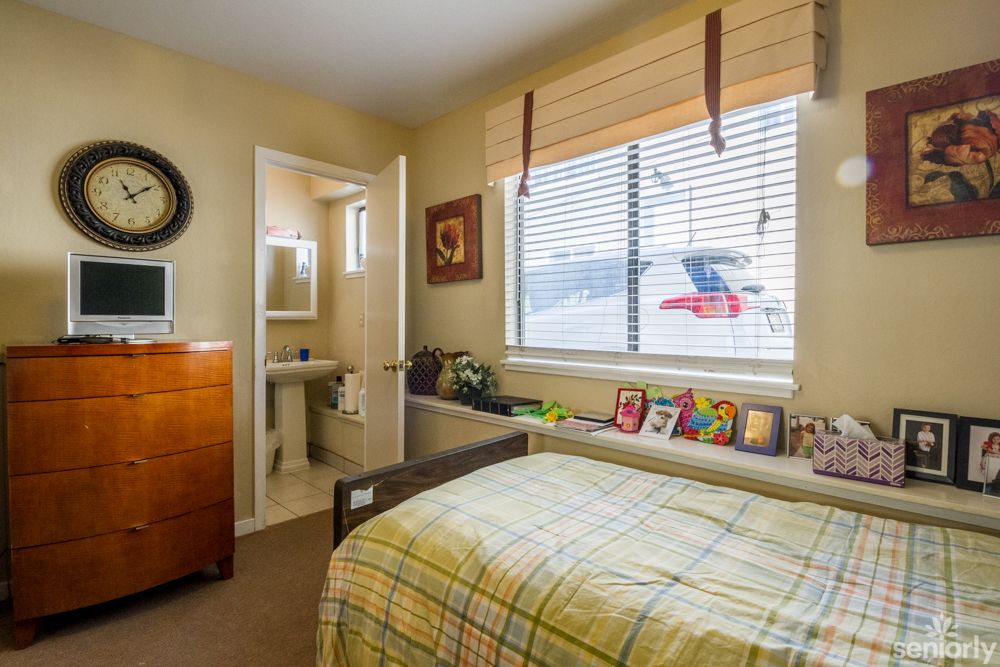 A cozy bedroom with a bed, window blinds, and an adjoining bathroom.
