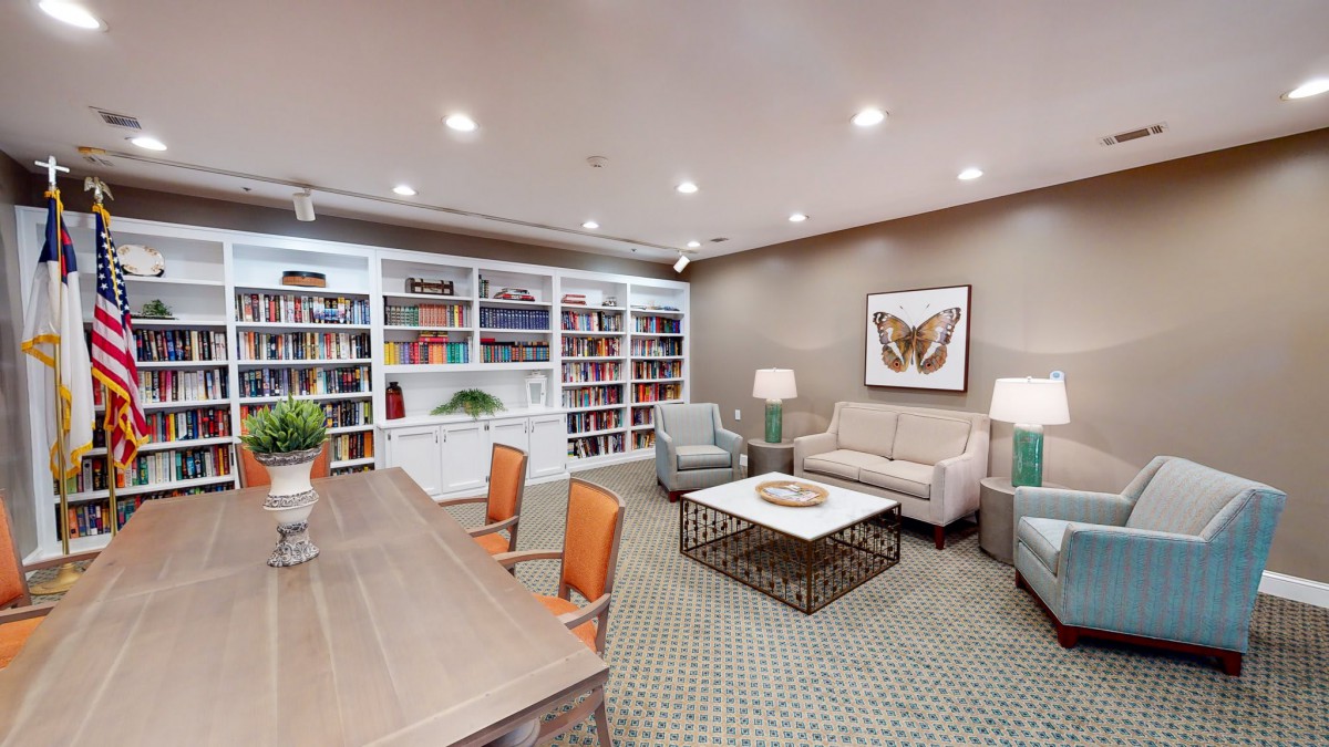 A cozy library with a large bookshelf, comfortable seating, and decorative artwork.