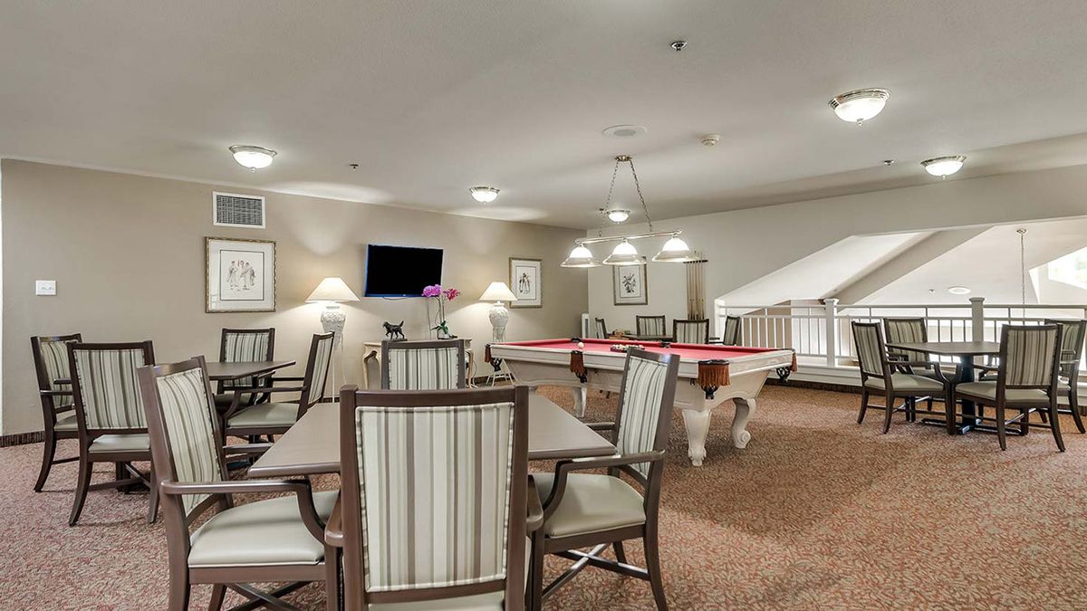 A modern game room featuring pool tables, a seating area, and a television.