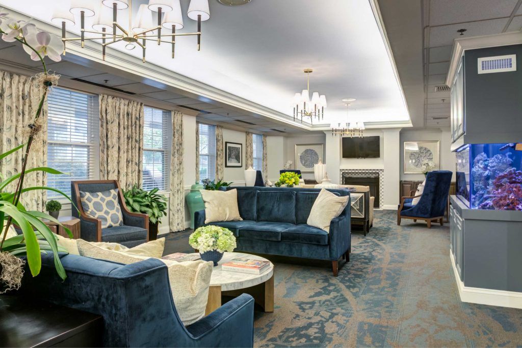 A modern living room with elegant blue sofas, decorative plants, and chandeliers.