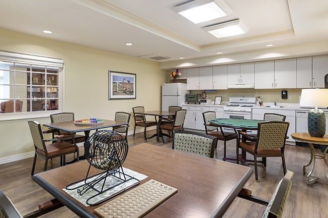 A modern dining and kitchen area with several tables and chairs, designed as a communal space.