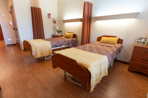 A well-appointed hospital room featuring two patient beds with warm bedding and soothing decor.