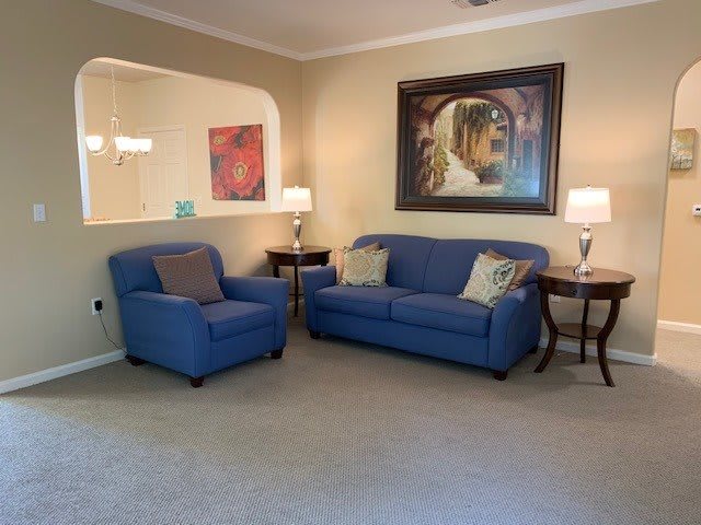 A cozy living room featuring a blue sofa and armchair with decorative lamps and artwork.