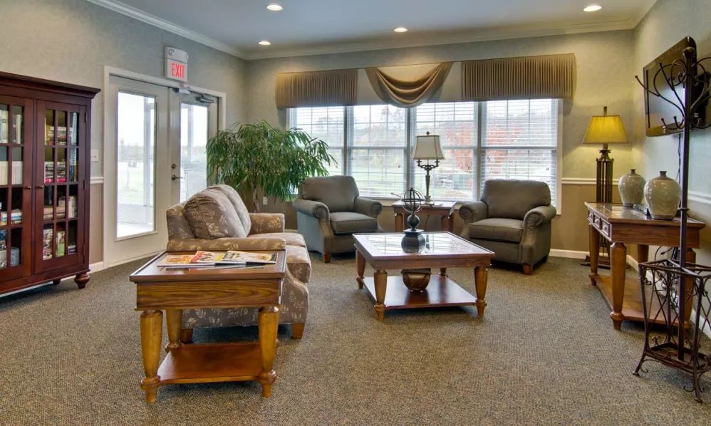 A cozy living room with comfortable sofas and a wooden coffee table, surrounded by large windows.