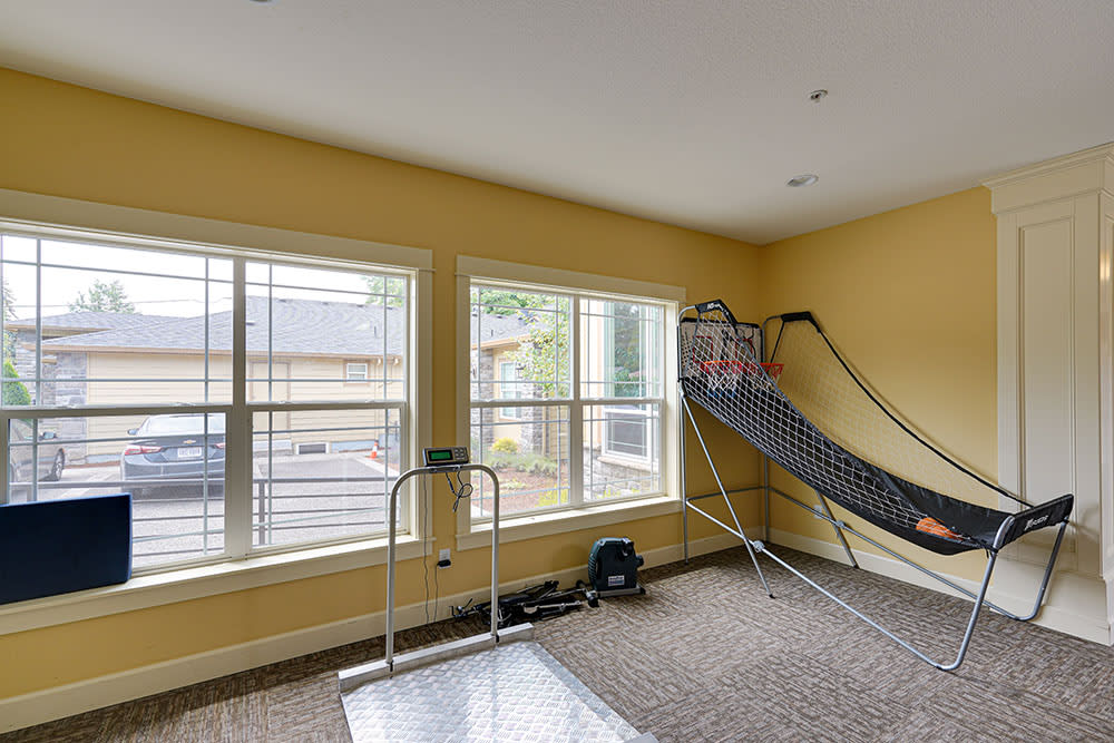 A game room featuring an indoor basketball hoop and large windows that allow natural light to fill the space.