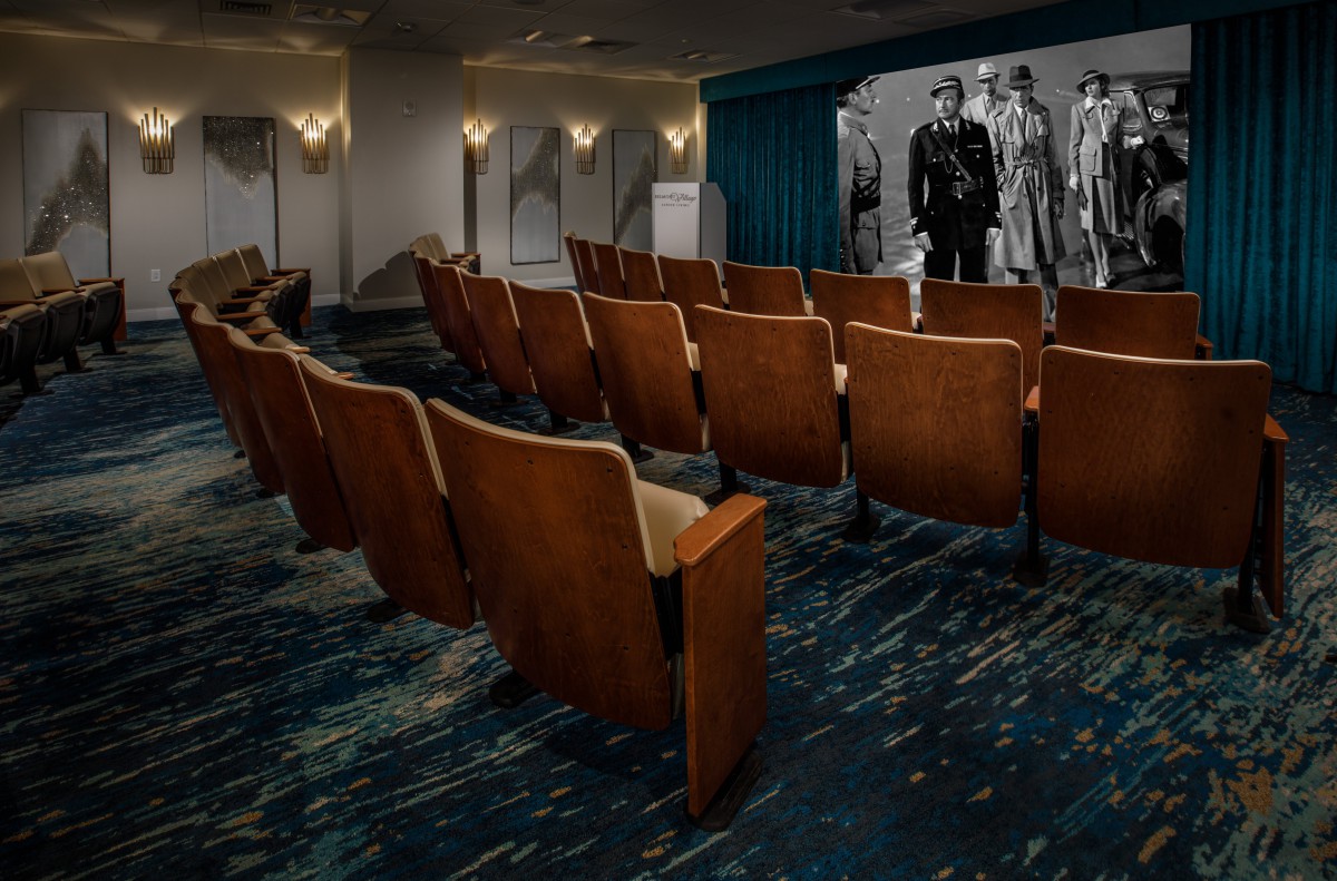 An empty theater with classic cinema seating and a retro film playing on the screen.