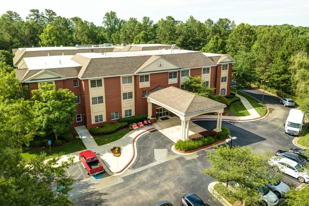 Aerial view of a building with a covered entrance and surrounding parking lot.