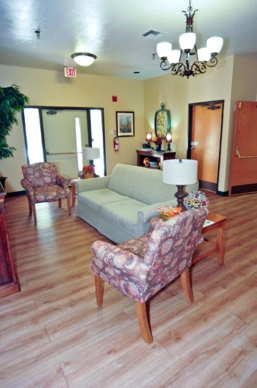 A cozy lobby area with sofas and chairs arranged around a central table, featuring warm lighting and decorative elements.