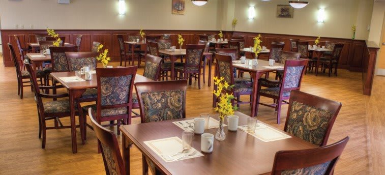 A cozy restaurant dining area with neatly arranged tables and chairs, featuring floral centerpieces and place settings.