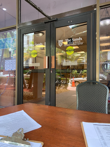 A view of the entrance to a restaurant, featuring glass doors and outdoor seating.