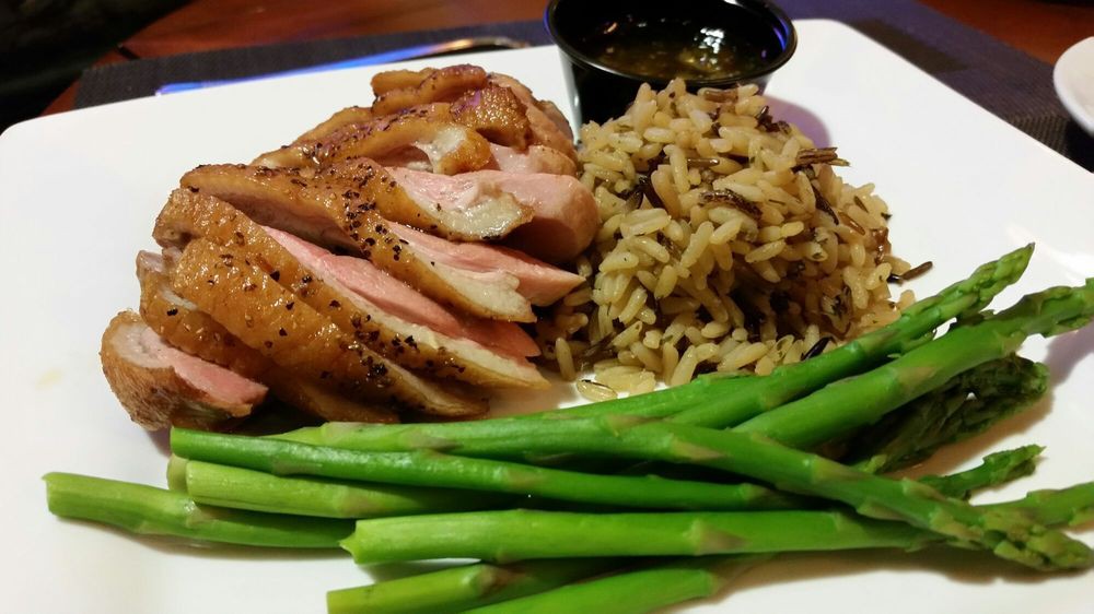 A delicious meal featuring sliced roasted meat, served with seasoned rice and fresh green beans.