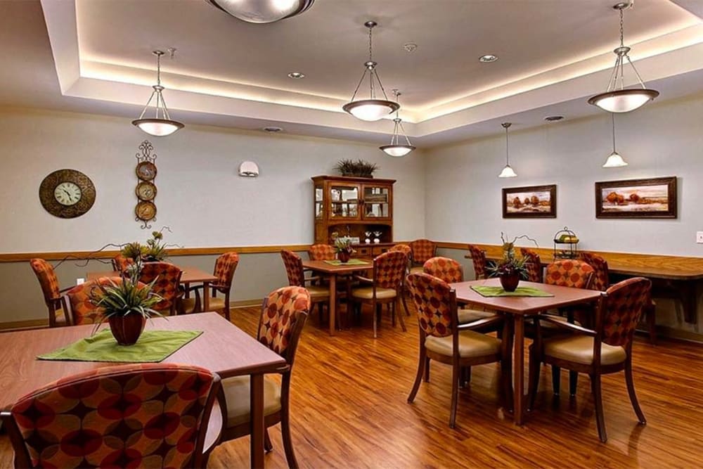 A cozy dining room with wooden tables and chairs arranged neatly, featuring warm lighting and tasteful decor.