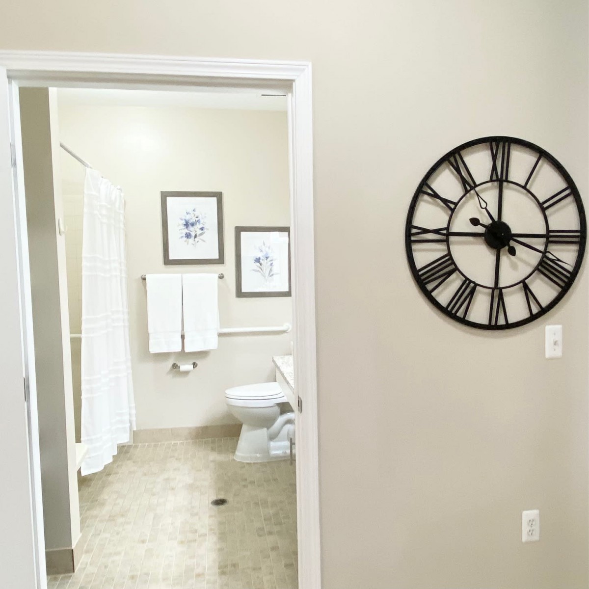 A modern bathroom view through a doorway with a decorative wall clock.