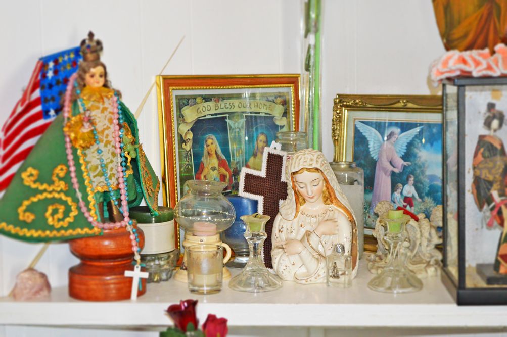 A home altar featuring various religious statues, icons, and candles.