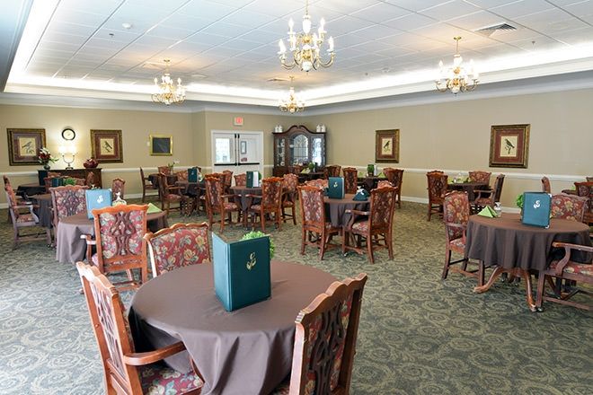 An elegantly decorated dining room with tables and chairs, lit by chandeliers.