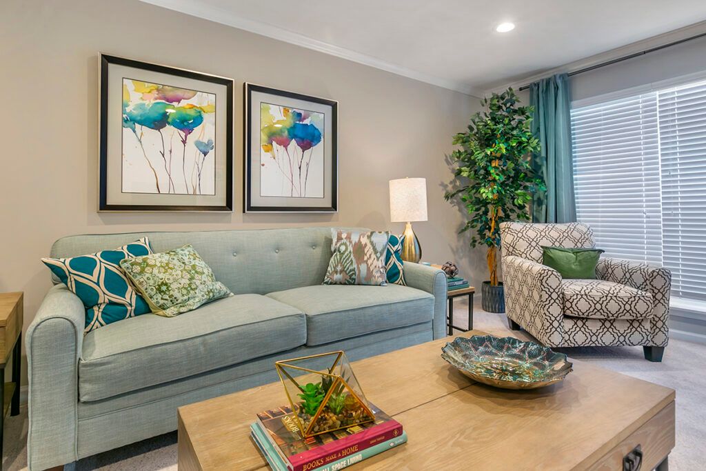 A cozy and well-decorated living room featuring a stylish sofa, vibrant artwork, and a lush green plant.