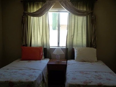 A cozy bedroom with twin beds and a window with curtains.