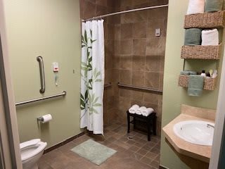 An accessible bathroom with a walk-in shower, grab bars, and tiled flooring.