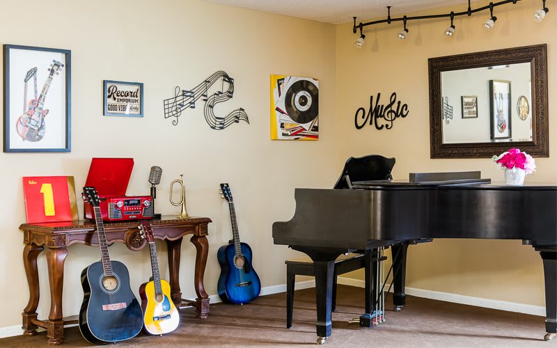 A cozy music room featuring a grand piano, several guitars, and decorative wall art.