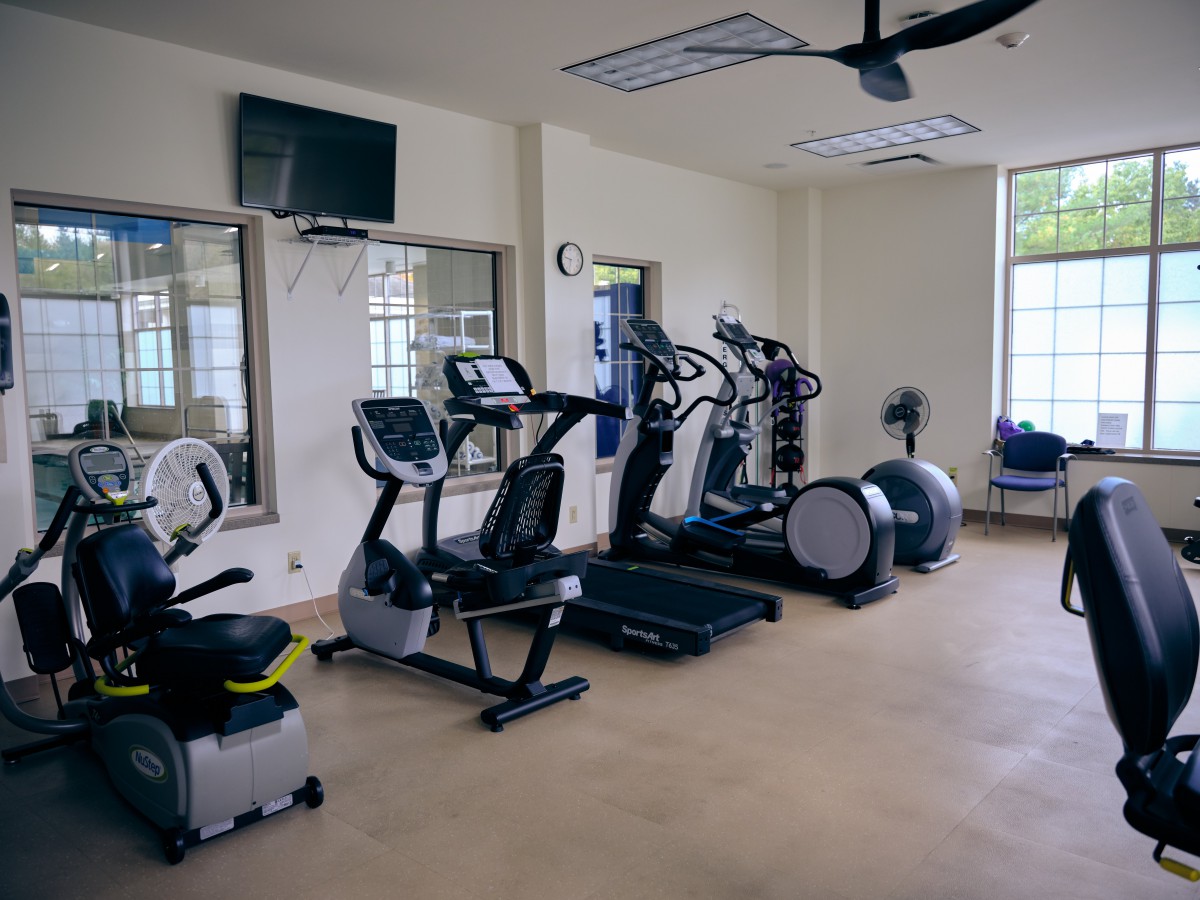 A gym equipped with various exercise machines, including treadmills, ellipticals, and stationary bikes.