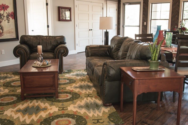 A cozy living room with leather sofas, a patterned rug, and wooden furniture.