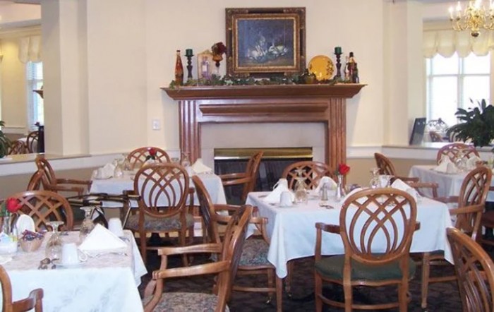 A cozy dining area featuring elegantly set tables and a warm fireplace.