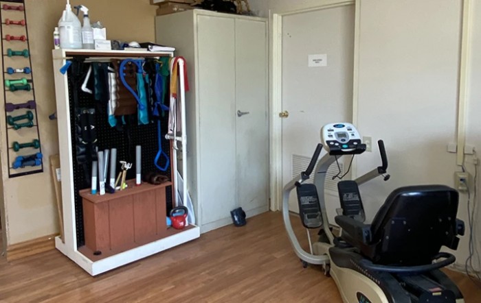 A home gym with a stationary bike and storage for workout gear.