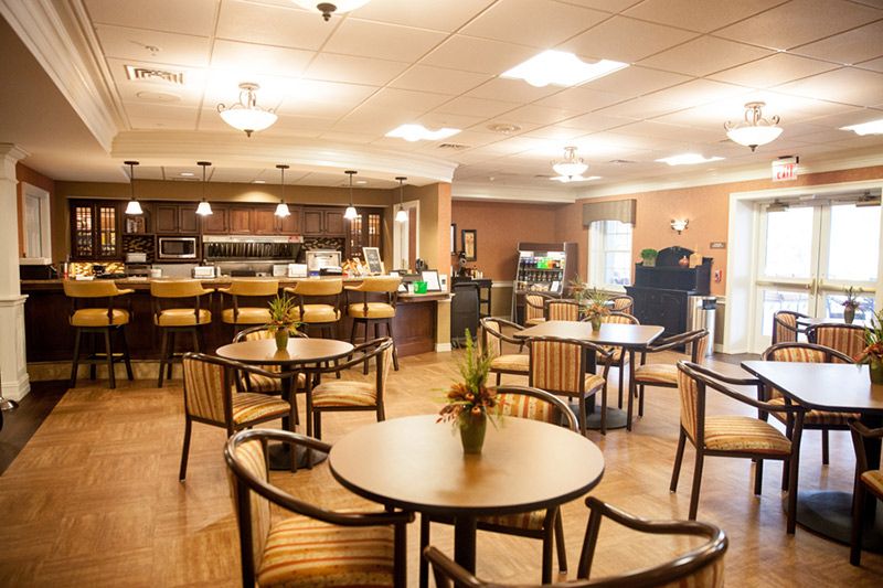 A cozy caf setting with neatly arranged tables and chairs, warmly lit for a welcoming ambiance.