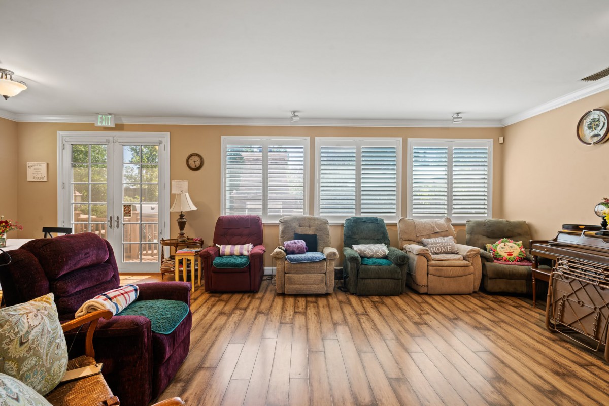 A cozy living room with a row of recliner chairs and large windows letting in natural light.