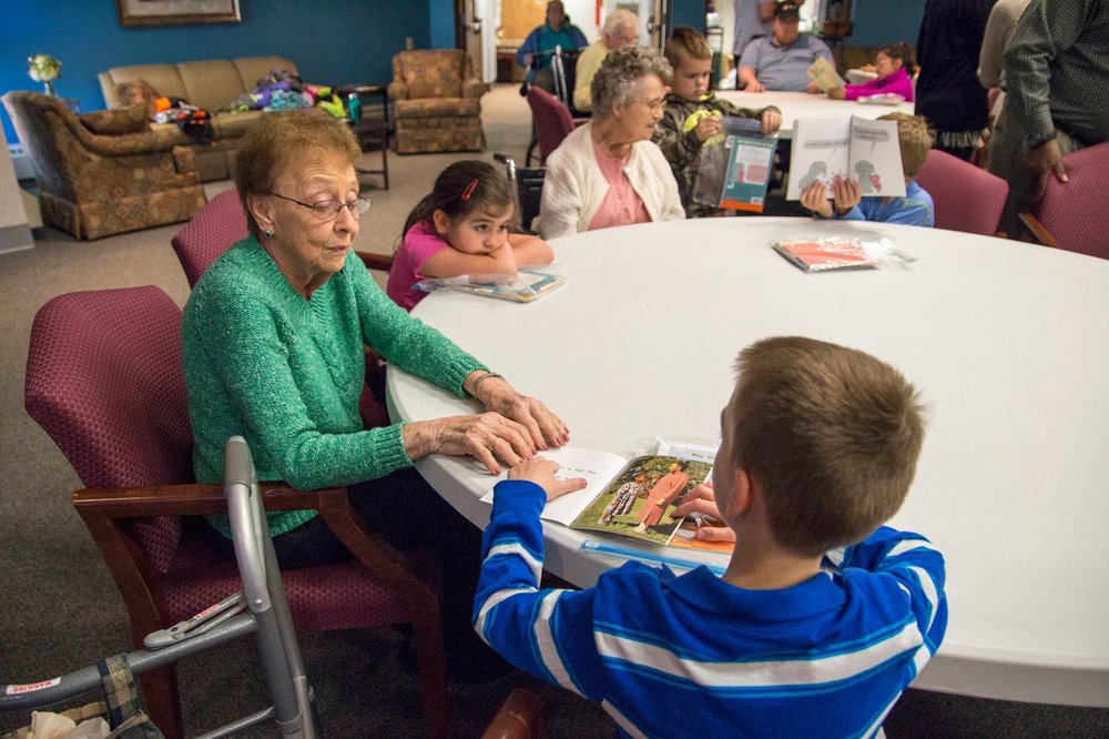 Children and seniors engaging in conversation around a table with books.