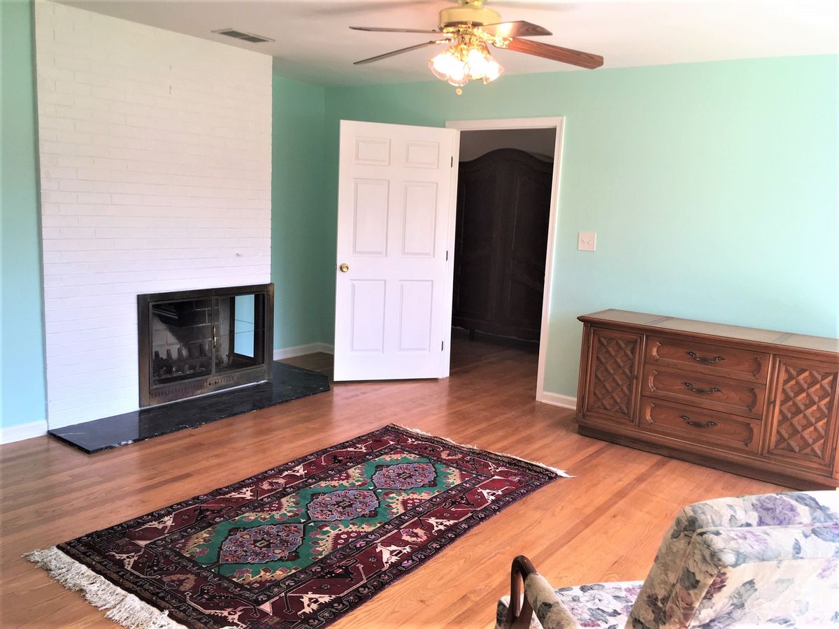 A cozy living room with a fireplace, hardwood floors, and a decorative rug.
