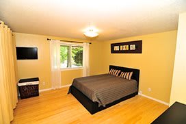 A cozy bedroom with a double bed, decorative pillows, and a window letting in natural light.