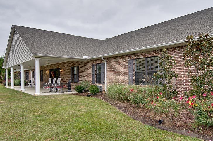 A brick house with a landscaped backyard and a covered patio.