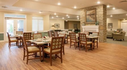 A cozy dining room with neatly arranged tables and chairs, featuring warm lighting and decorative elements.