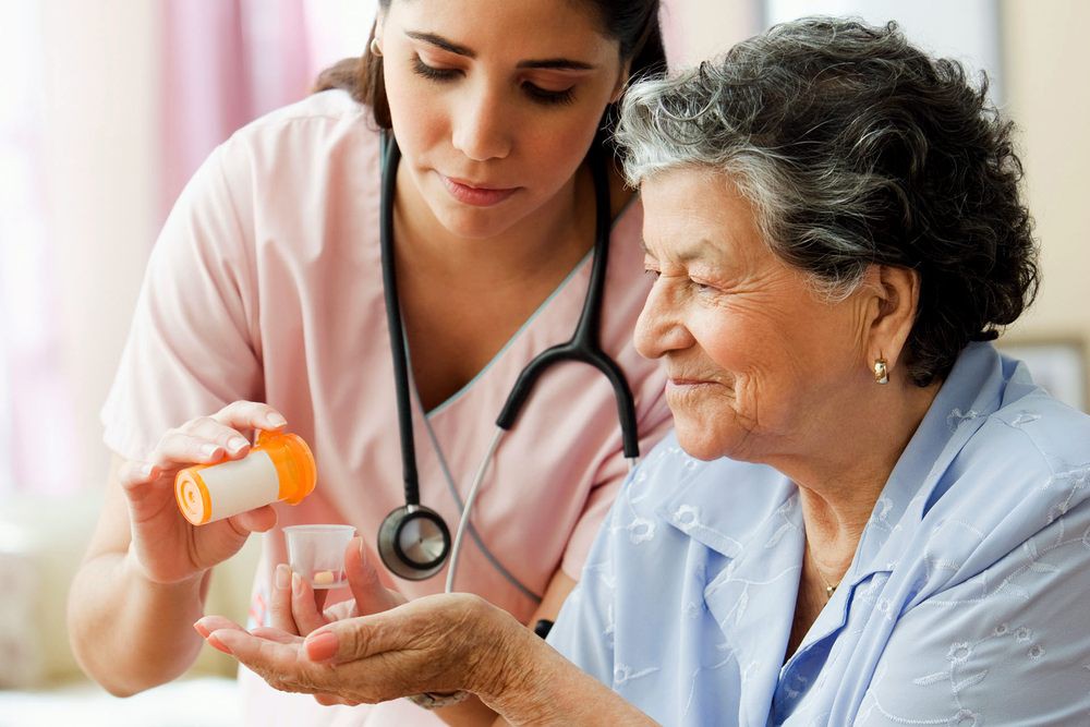 A nurse assists an elderly woman with medication.