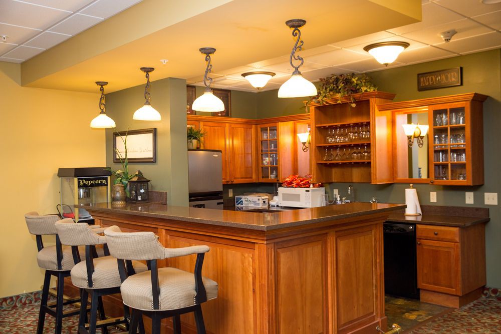 A modern kitchen featuring a wooden bar counter with pendant lighting and sleek wood cabinetry.