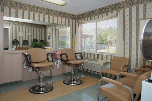 A stylish barber shop interior featuring comfortable chairs and ample natural light.
